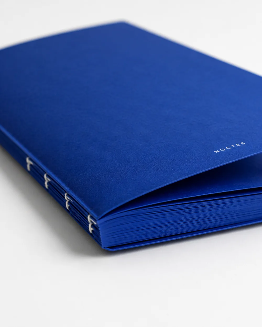 Cahier Noctes entrouvert, pages bleues et dos cousu